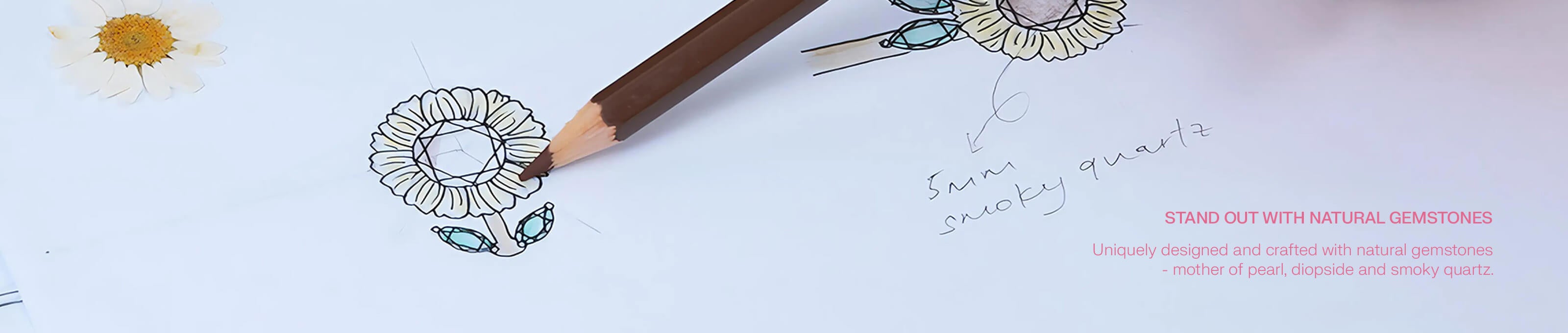 Hand holding a pencil with gemstone accents on a drawing of flowers, text about natural gemstones. "Stand out with natural gemstones, uniquely designed and crafted with natural gemstones - mother of pearl, diopside and smoky quartz."