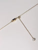 A close-up video demonstrating how to adjust the length of a gold necklace. The camera focuses on the clasp area, which features a lobster clasp, a small gold slider ball, and a delicate chain end with a small charm. The video then shows the end of the chain being gently pulled through the slider ball, illustrating the smooth adjustment mechanism.