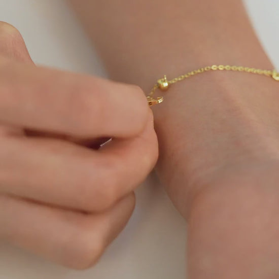 Step-by-step video of a person putting on an adjustable bracelet, fastening it securely and adjusting it to fit their wrist.