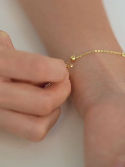 Step-by-step video of a person putting on an adjustable bracelet, fastening it securely and adjusting it to fit their wrist.
